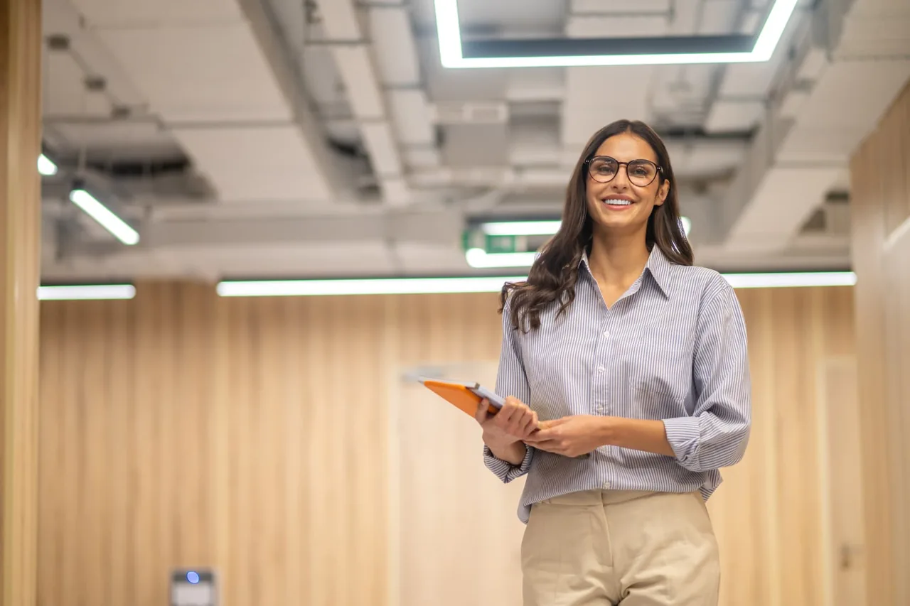 Profesional sonriendo con una carpeta en un campus corporativo
